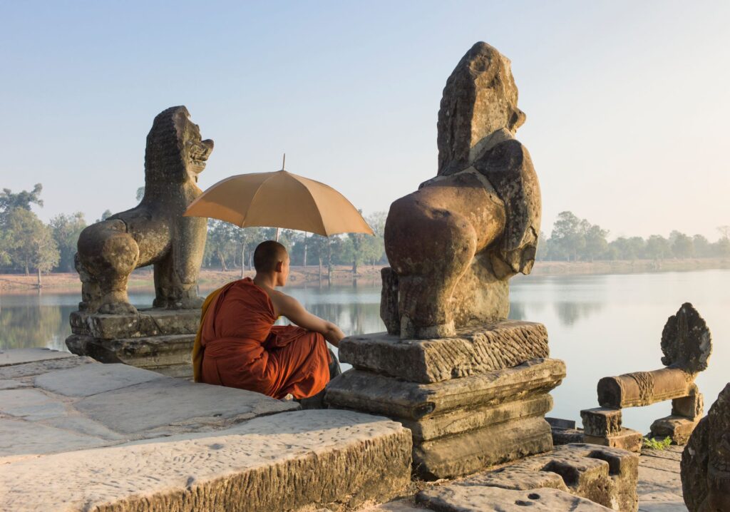 a-asia-cambodia-buddhist-monk-sitting-next-to-water-at-sunrise-589155628-g