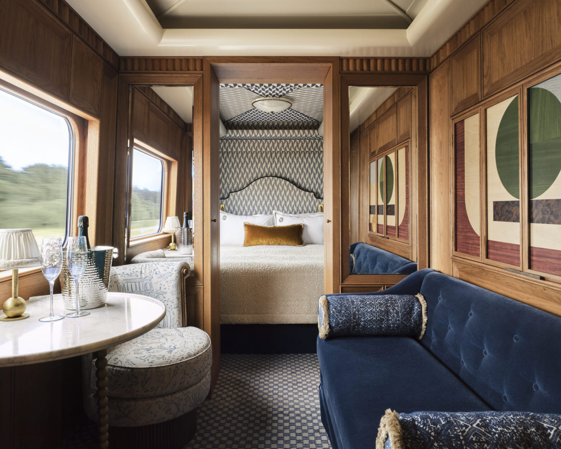 Wood-panelled Grand Suite aboard the Britannic Explorer train, with a blue velvet sofa and private bedroom.