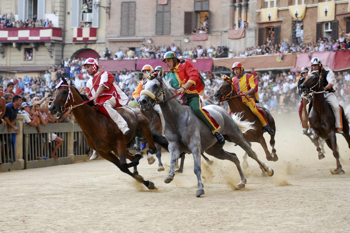 Jockeys racing horses around Piazza del Campo during the historic Palio in Siena, Italy.